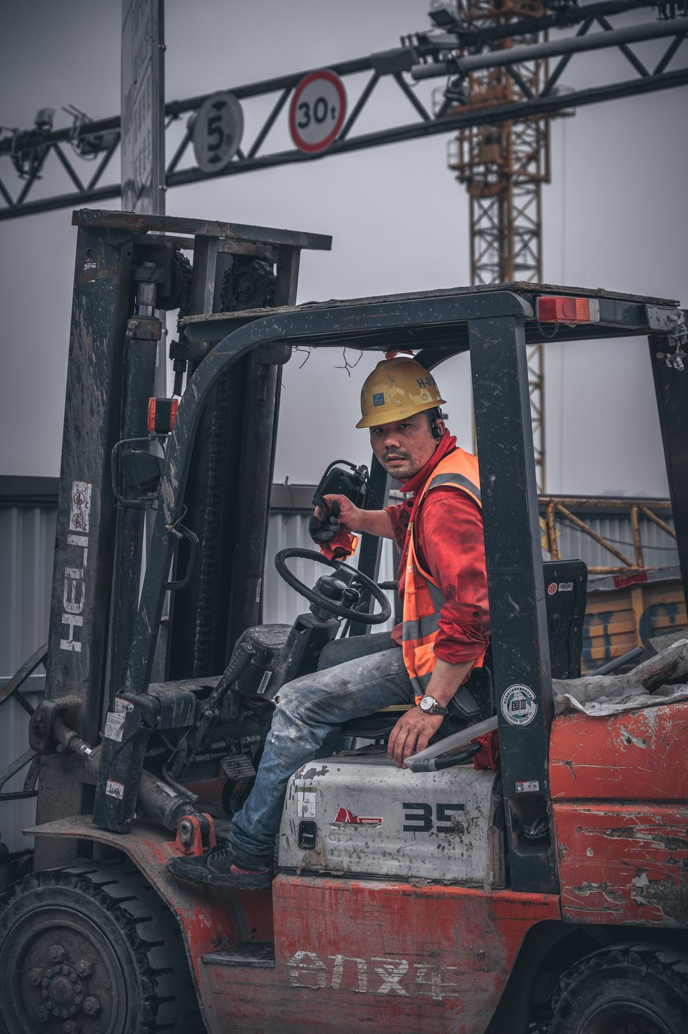 Forklift operator in a hard hat and high-visibility vest at the loading yard
